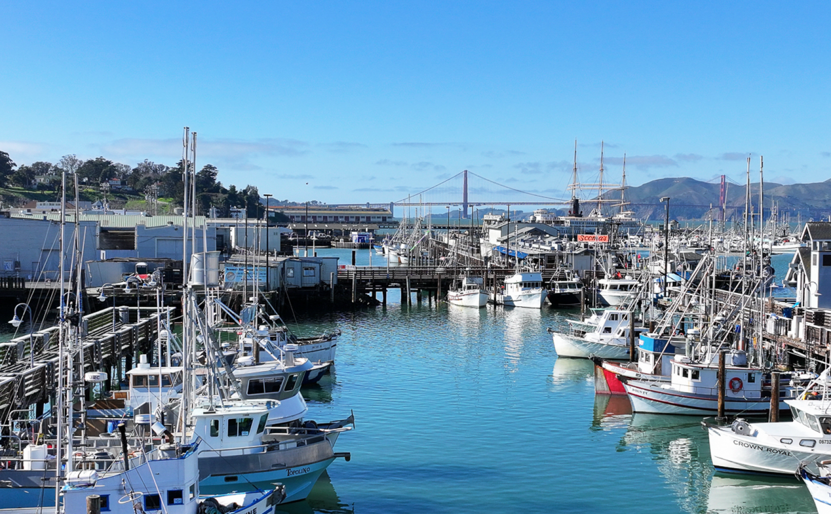 Fisherman's Wharf lagoon with colorful fishing boats and a view of Golden Gate Bridge