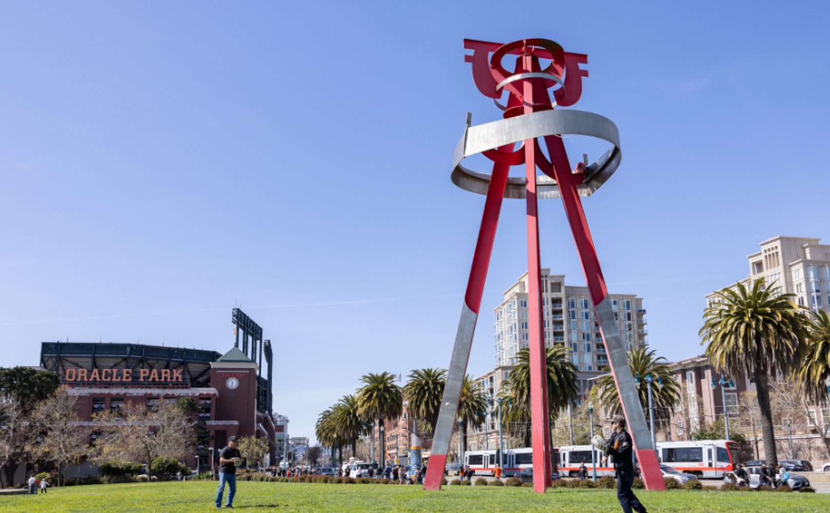 Two people playing catch next to Sea Change sculpture