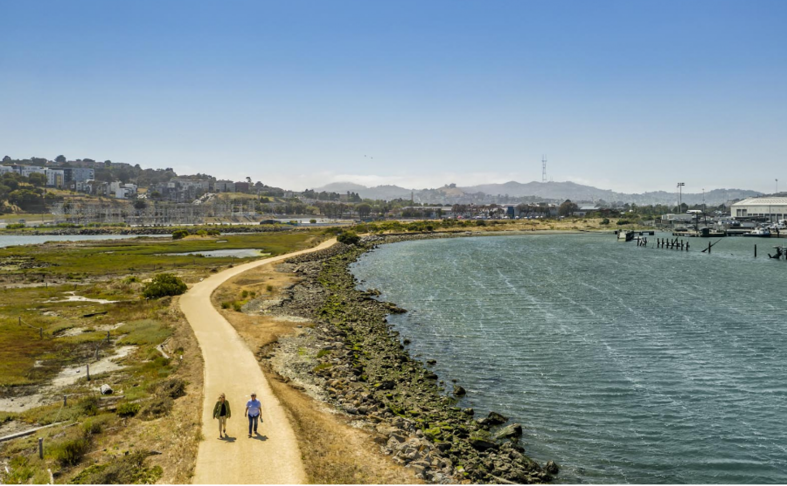 Two people walking on a gravel path at a park.