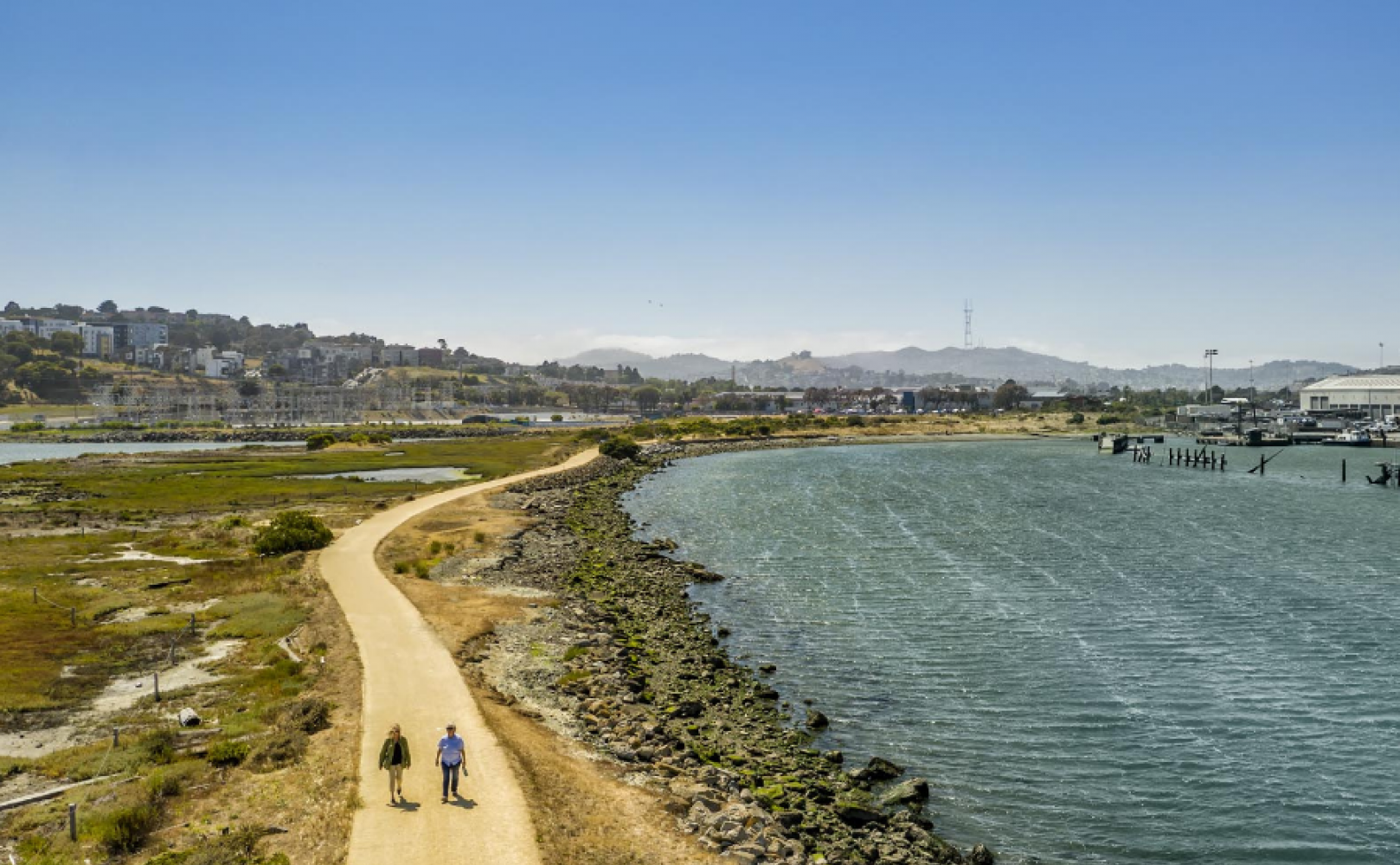 Two people walking on a gravel path at a park.