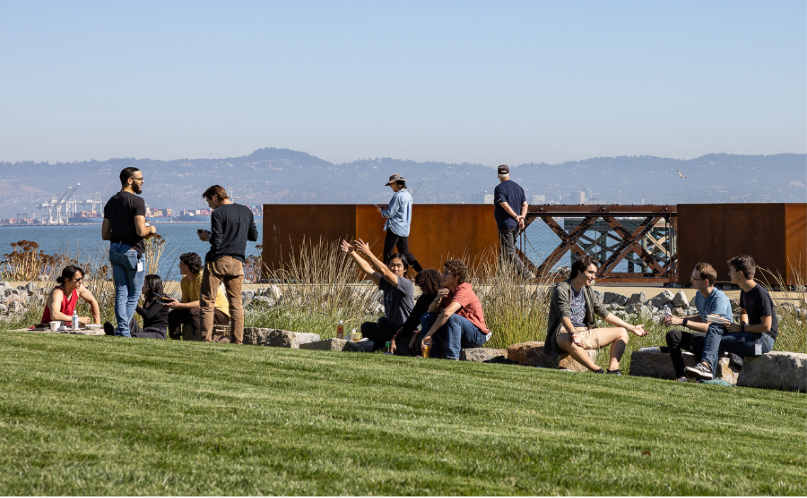 People sitting along a rock wall at a park
