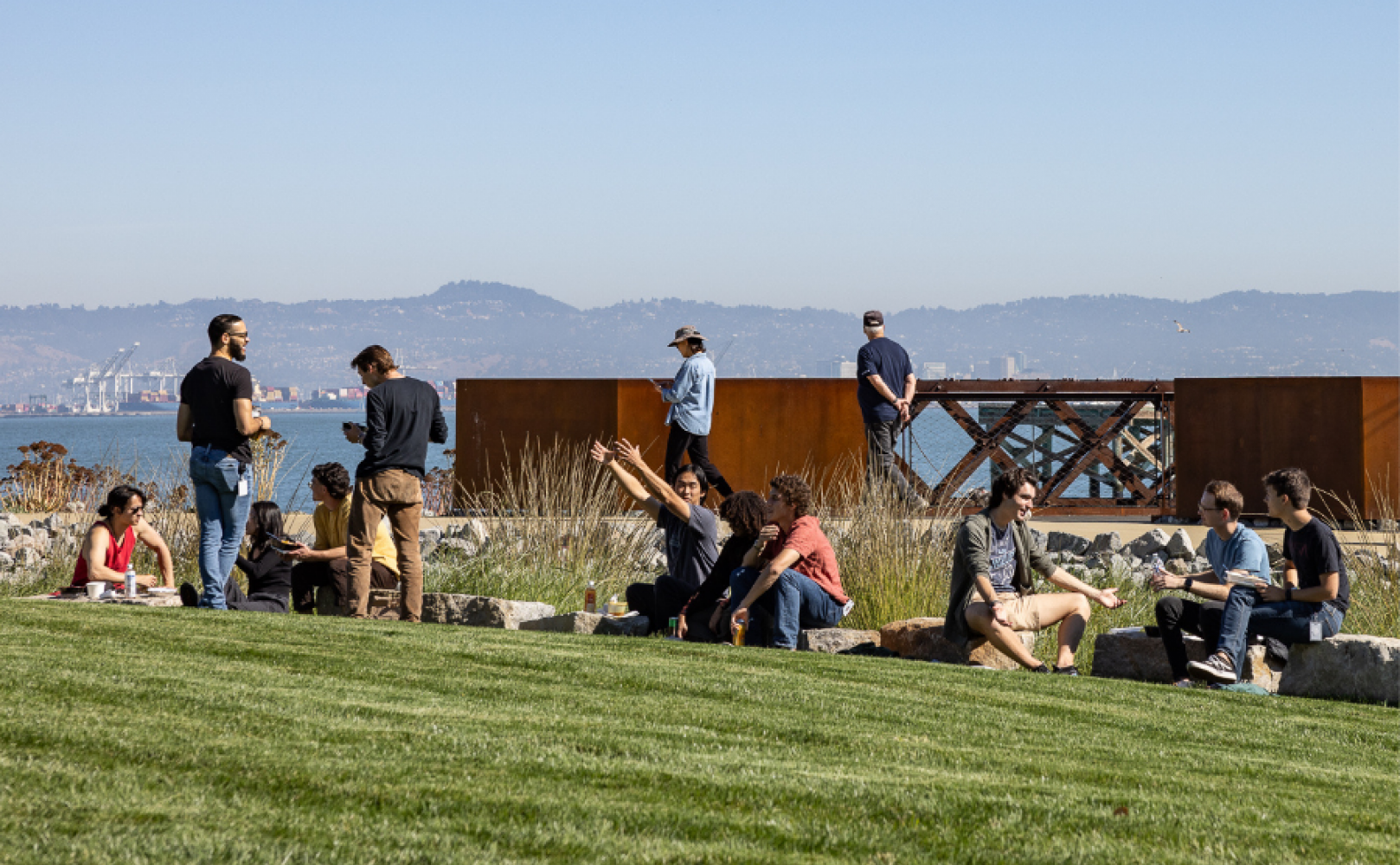People sitting along a rock wall at a park