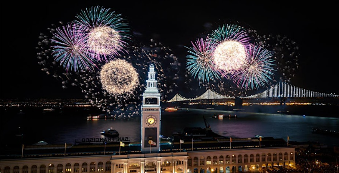 Fireworks explode in the night sky behind the Ferry Building