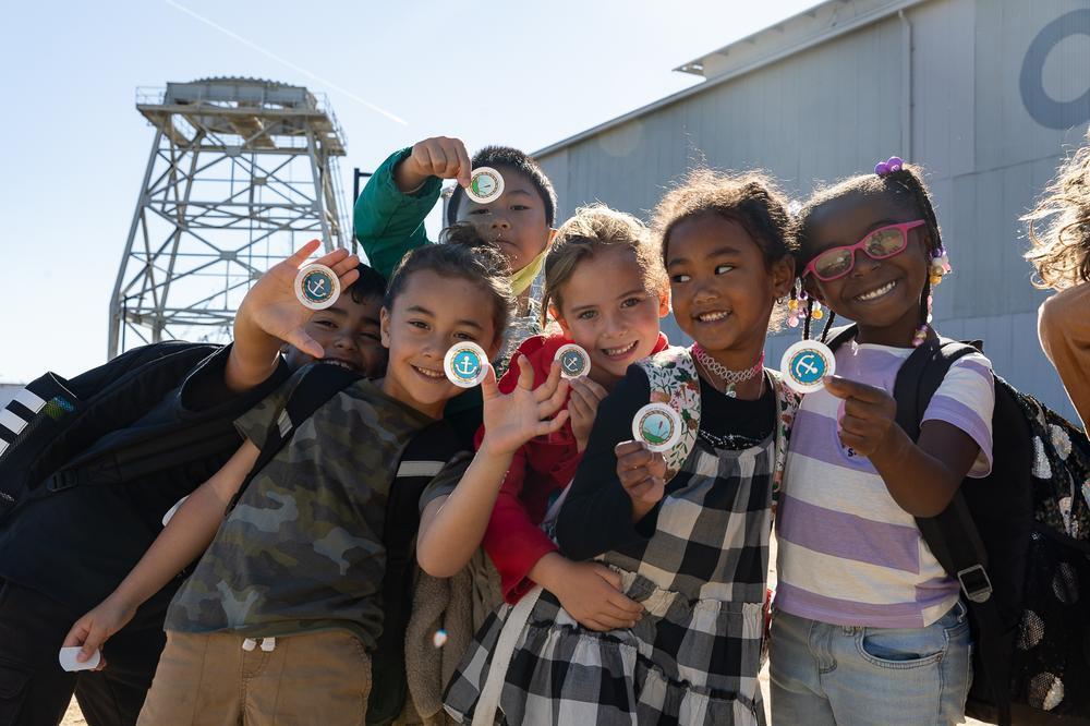 Local San Francisco students show their stickers to the camera at Crane Cove Park.