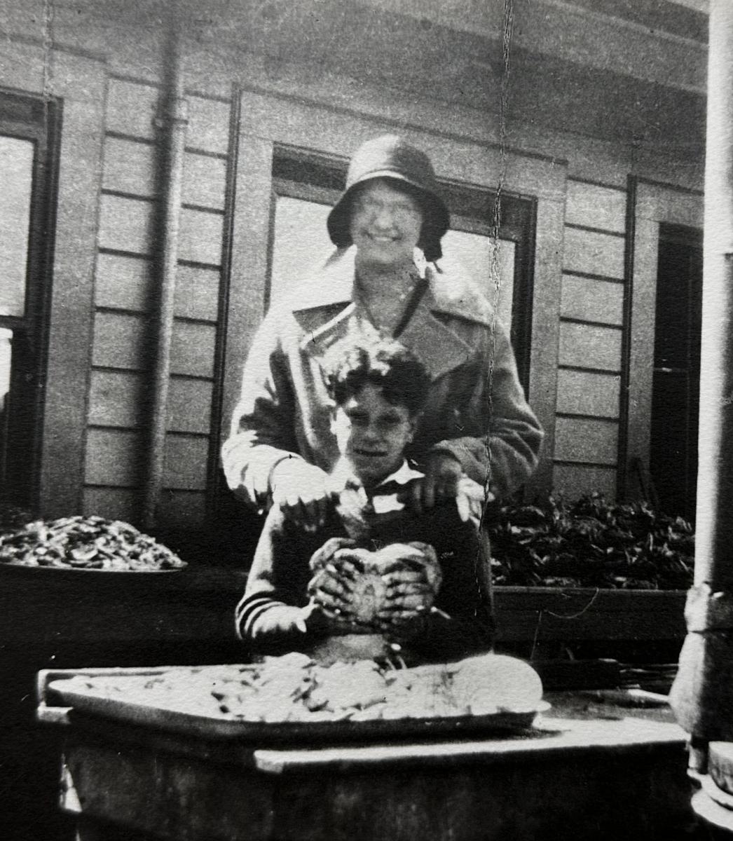 Historic&nbsp;image&nbsp;of&nbsp;a&nbsp;young&nbsp;boy&nbsp;and&nbsp;an&nbsp;older female relative showing off a crab in front of a cooker, circa 1915.&nbsp;