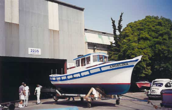 A&nbsp;painted sailboat on wheels surrounded by a group of people on the street.&nbsp;
