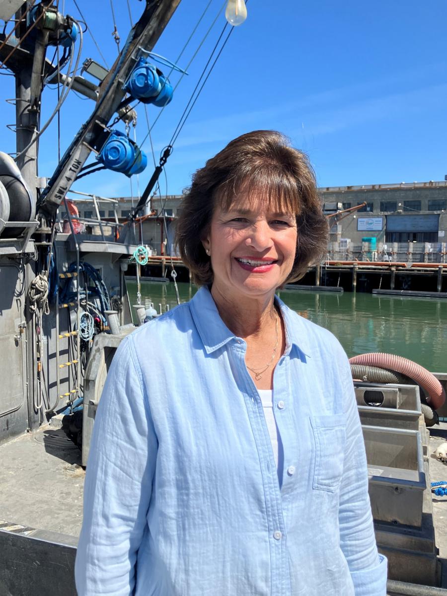 Jeanette Caito smiles in front of Pier 45 with&nbsp;the&nbsp;Caito Fisheries sign in the background.&nbsp;