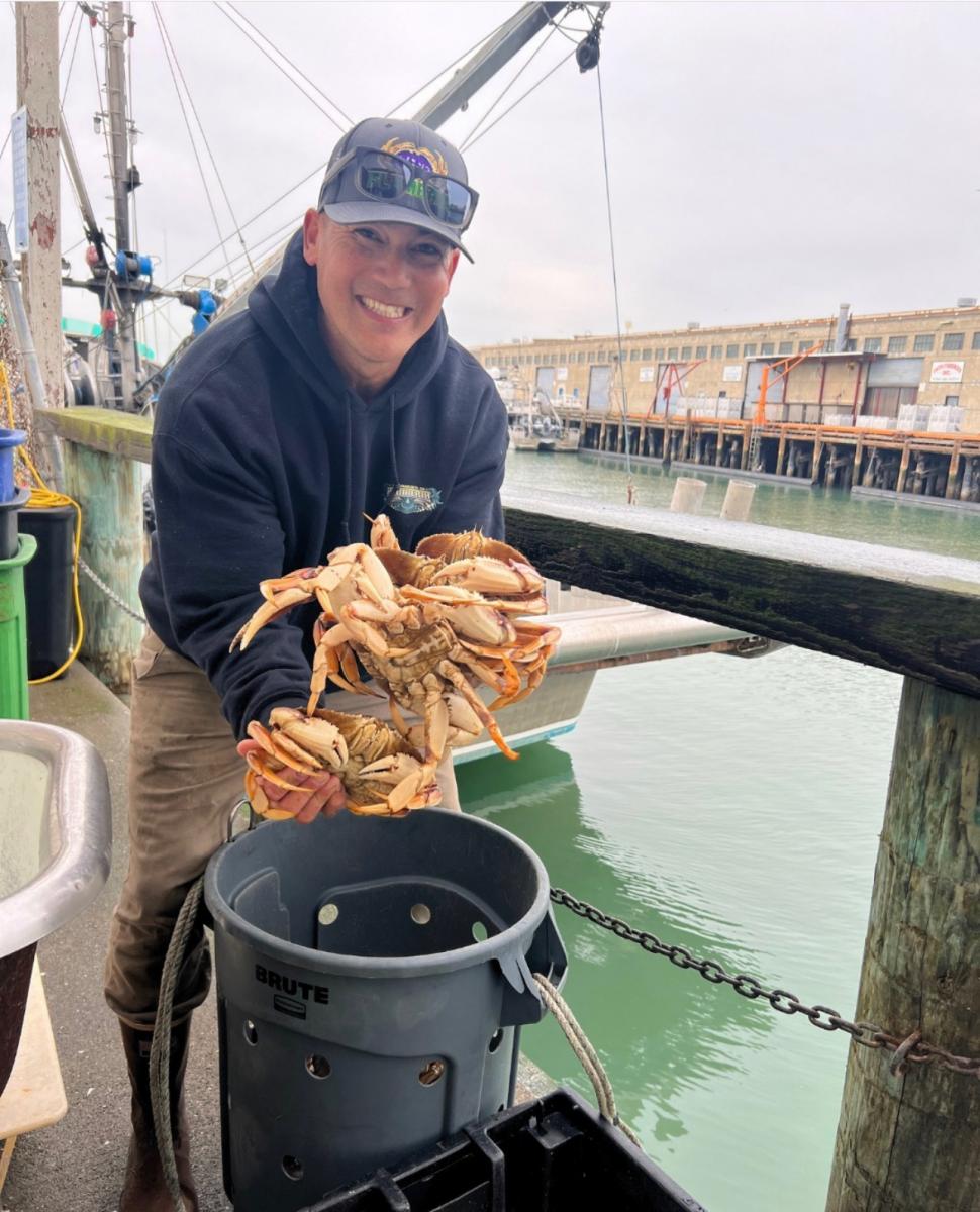 &nbsp;A fisherman&nbsp;smiles,&nbsp;holding&nbsp;up&nbsp;crabs.