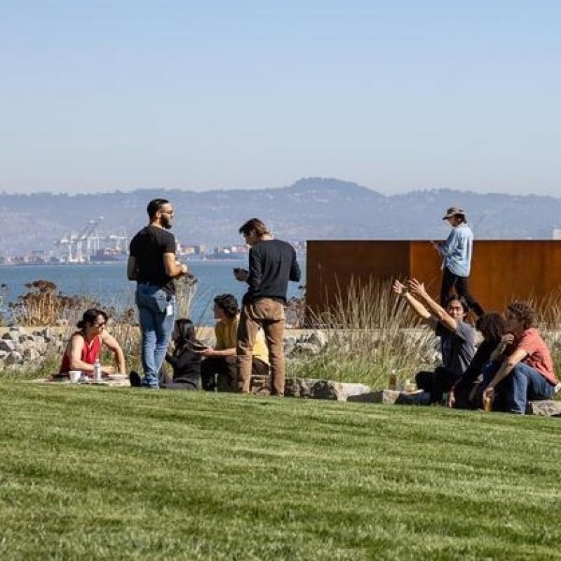 People talking while sitting on the grass lawn at Bayfront Park