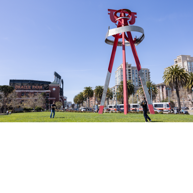 Two people playing catch next to Sea Change sculpture