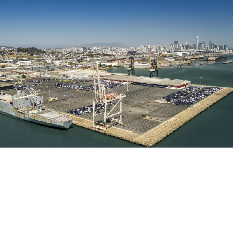 Cars parked in neat rows on a massive pier with cranes